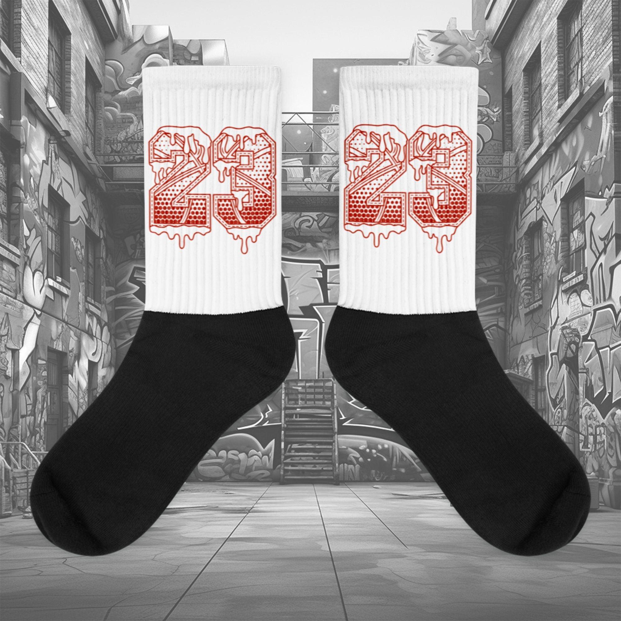 Showcases the view of the socks, highlighting the vibrant ' 23 Ball ' design, which perfectly complements the Air Jordan 11 Cherry sneakers. The intricate pattern and color scheme inspired by the theme are prominently displayed. Focusing on the ribbed leg , cusioned bottoms and the snug fit of the socks. This angle provides a clear view of the texture and quality of the material blend