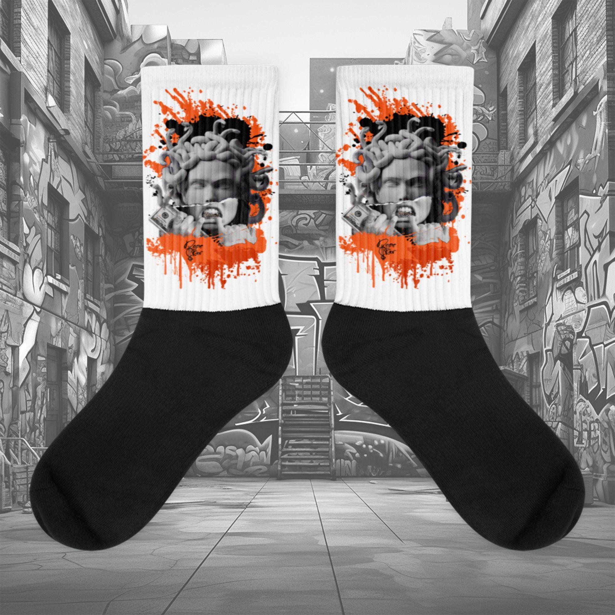 Showcases the view of the socks, highlighting the vibrant ' MEDUSA' design, which perfectly complements the Air Jordan 12 Retro WNBA All-Star Brilliant Orange sneakers. The intricate pattern and color scheme inspired by the theme are prominently displayed. Focusing on the ribbed leg , cusioned bottoms and the snug fit of the socks. This angle provides a clear view of the texture and quality of the material blend.