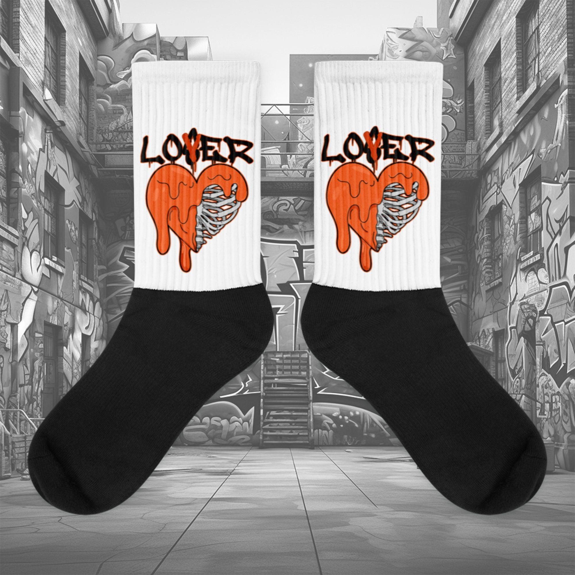 Showcases the view of the socks, highlighting the vibrant ' Lover Loser ‘ design, which perfectly complements the Air Jordan 12 Retro WNBA All-Star Brilliant Orange sneakers. The intricate pattern and color scheme inspired by the theme are prominently displayed. Focusing on the ribbed leg , cusioned bottoms and the snug fit of the socks. This angle provides a clear view of the texture and quality of the material blend.
