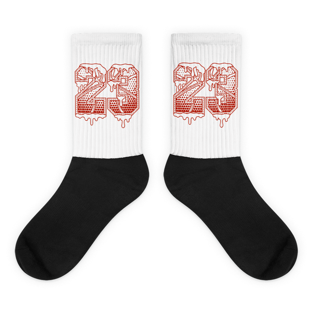 Showcases the view of the socks, highlighting the vibrant ' 23 Ball ' design, which perfectly complements the Air Jordan 11 Cherry sneakers. The intricate pattern and color scheme inspired by the theme are prominently displayed. Focusing on the ribbed leg , cusioned bottoms and the snug fit of the socks. This angle provides a clear view of the texture and quality of the material blend