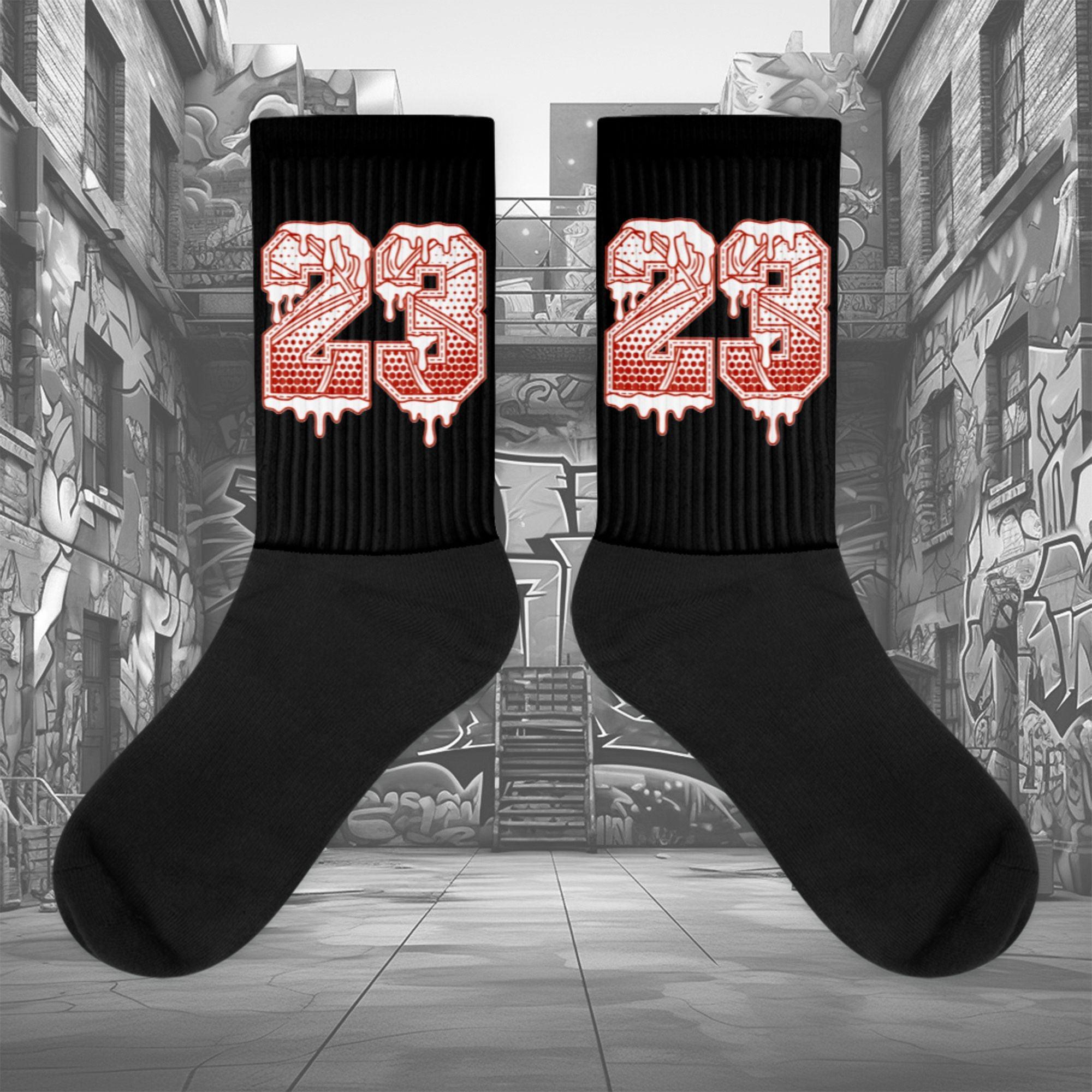 Showcases the view of the socks, highlighting the vibrant ' 23 Ball ' design, which perfectly complements the Air Jordan 11 Cherry sneakers. The intricate pattern and color scheme inspired by the theme are prominently displayed. Focusing on the ribbed leg , cusioned bottoms and the snug fit of the socks. This angle provides a clear view of the texture and quality of the material blend