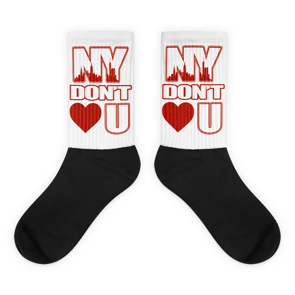 Showcases the view of the socks, highlighting the vibrant ' NY Don’t Love U ' design, which perfectly complements the Air Jordan 11 Cherry sneakers. The intricate pattern and color scheme inspired by the theme are prominently displayed. Focusing on the ribbed leg , cusioned bottoms and the snug fit of the socks. This angle provides a clear view of the texture and quality of the material blend.
