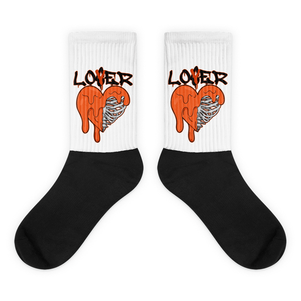 Showcases the view of the socks, highlighting the vibrant ' Lover Loser ‘ design, which perfectly complements the Air Jordan 12 Retro WNBA All-Star Brilliant Orange sneakers. The intricate pattern and color scheme inspired by the theme are prominently displayed. Focusing on the ribbed leg , cusioned bottoms and the snug fit of the socks. This angle provides a clear view of the texture and quality of the material blend.